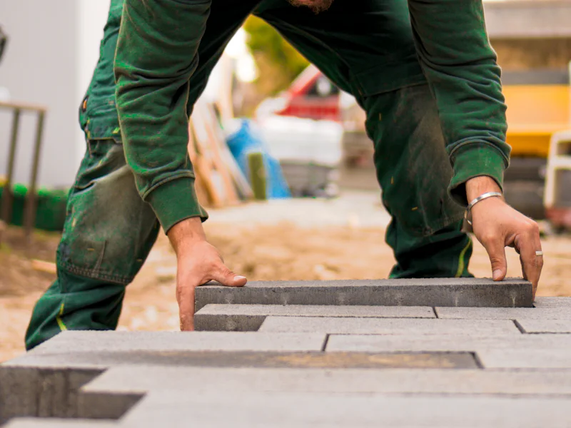 A worker setting gray pavers into a new walkway